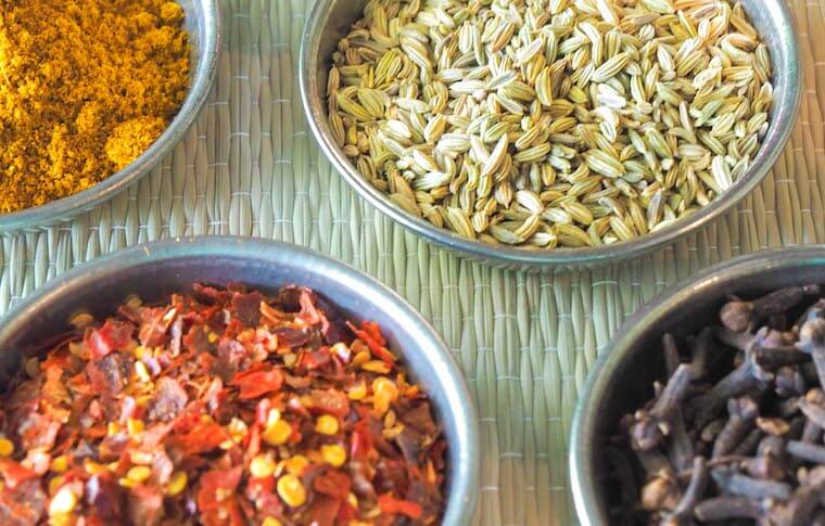 Six colorful spices in metal jars laying on a table