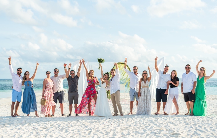 newly weds and their guests waving happily on the beach